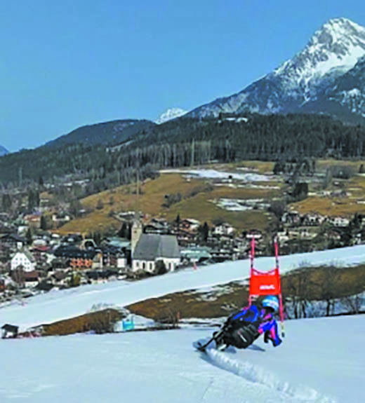 Shona skiing down a slope, mountains and village in the background.
